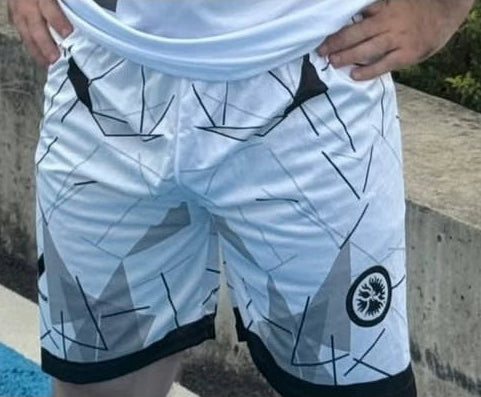 Person wearing a white shorts with black patterns by a poolside